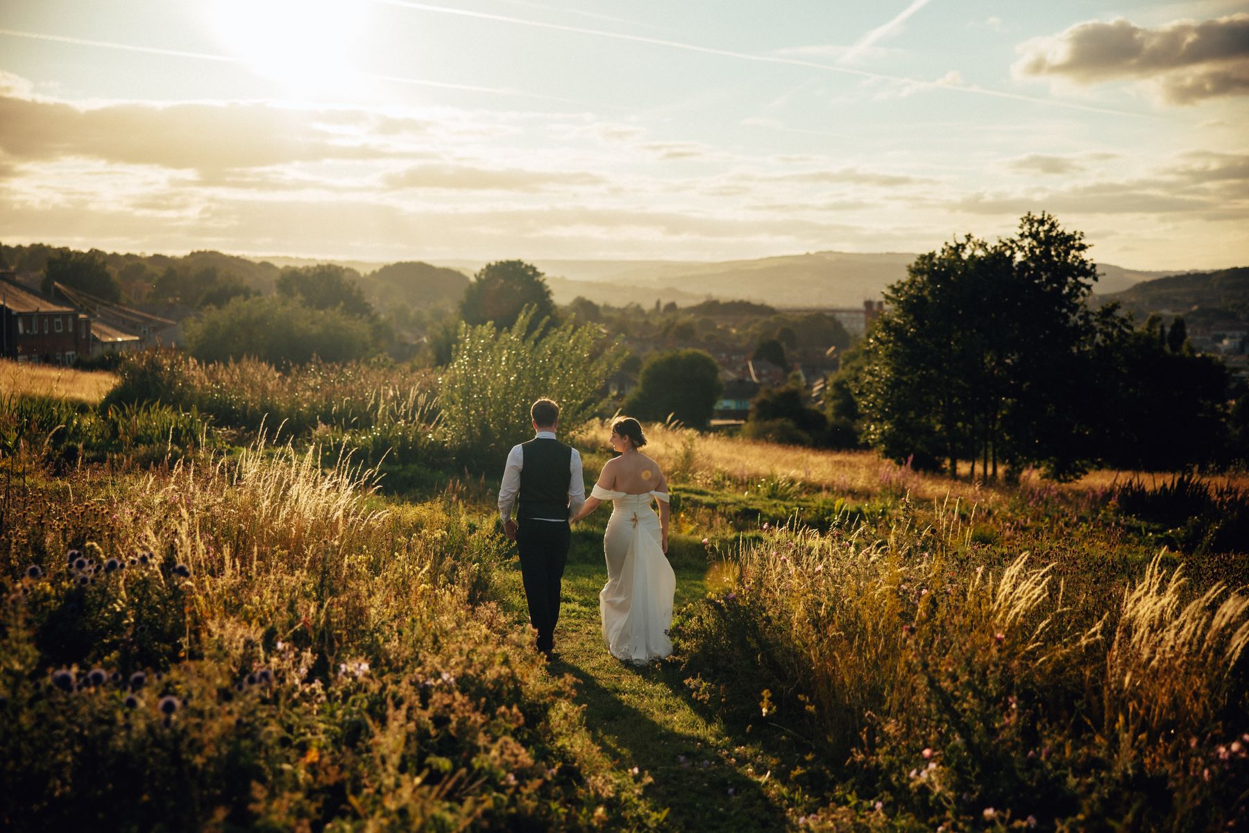 A couple walking out across a hillside at golden hour